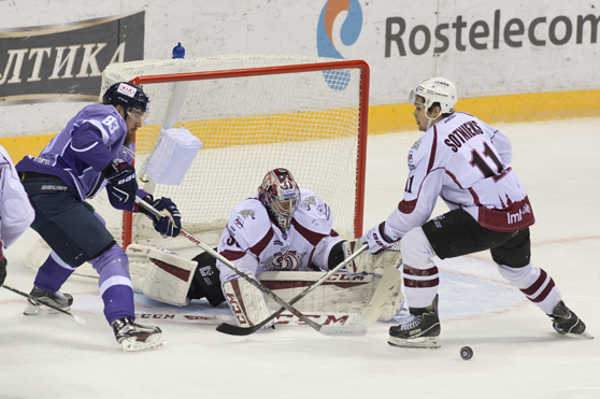 Na snímke zľava Lukáš Kašpar (Slovan), brankár Jakub Sedláček a Kristaps Sotnieks (Dinamo) v hokejovom stretnutí KHL med