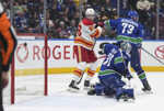 Zľava slovenský útočník Calgary Samuel Honzek, brankár Canucks Arturs Silovs a jeho spoluhráč Vincent Desharnais.
