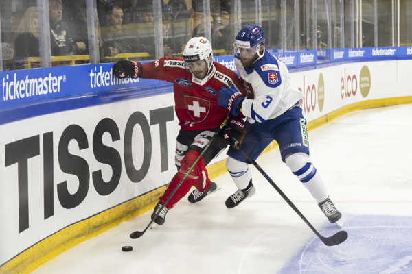 Slovenský hokejista Adam Jánošík (vpravo) v súboji o puk so Švajčiarom Christophom Bertschym.