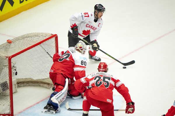 Kapitán Kanady Sidney Crosby (v pozadí), brankár Dánska Frederik Dichow (uprostred) a hokejista Dánska Oliver Lauridsen.