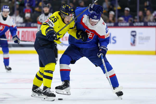 Slovenský hokejista Tomáš Chrenko vpravo a hráč Švédska Casper Juustovaara bojujú o puk počas zápa.